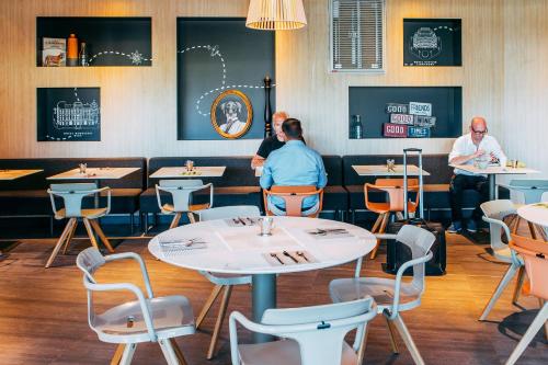 a restaurant with tables and chairs and people sitting at tables at Novotel Paris Coeur d'Orly Airport in Orly