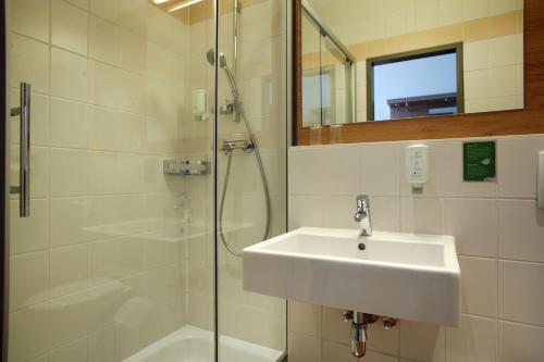 ein Bad mit einem Waschbecken und einer Dusche in der Unterkunft Hotel Babenbergerhof in Mödling