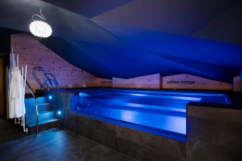 a swimming pool in a room with blue lighting at Hotel Tremoggia in Chiesa in Valmalenco