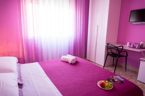 a pink room with a bed with a bowl of fruit on it at Colors B&B in Palermo