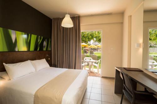 a bedroom with a bed and a desk and a patio at Mayfair Gardens in Paphos
