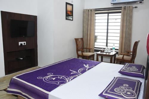- une chambre dotée d'un lit avec des draps violets et blancs dans l'établissement Alakhnanda Guest House, à Varanasi