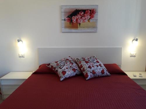 1 dormitorio con 1 cama roja y 2 almohadas en Affittacamere b&b Il FIORE en Posada