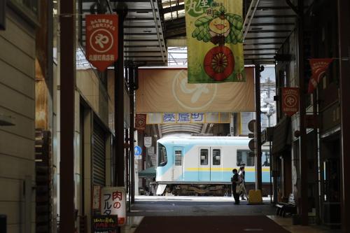 a person walking in an alley with a train in the background at Hotel Koo Otsuhyakucho in Otsu