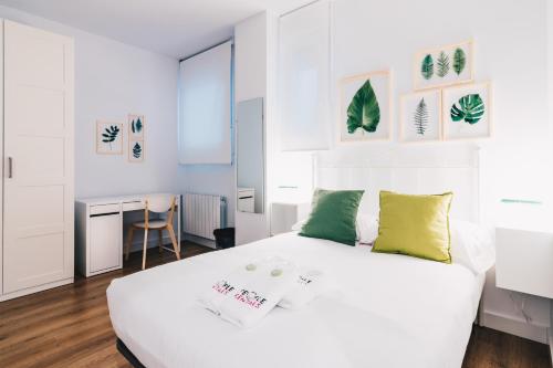 ビルバオにあるBilbao Home Apartment by People Rentalsの白いベッドルーム(緑の枕が付いた大きな白いベッド付)