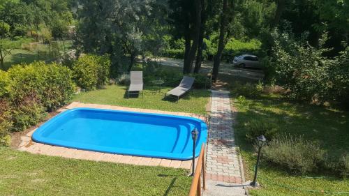 a blue swimming pool in a yard with two chairs at Joó House in Balatonfüred