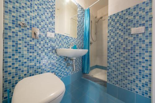 un bagno piastrellato blu con un water e un lavandino di Casa Scilocco a San Vito lo Capo