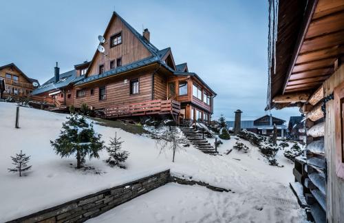 a large wooden house with snow on the ground at Penzión Michal in Ždiar