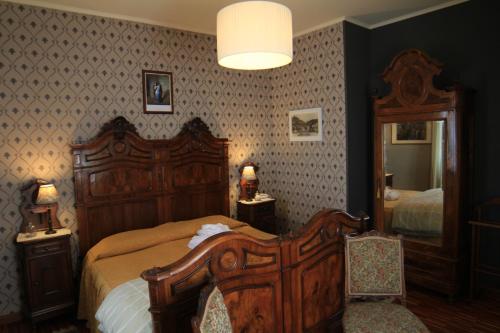a bedroom with a wooden bed and a mirror at Felicin - Ristorante Albergo "Dimora Storica" in Monforte dʼAlba