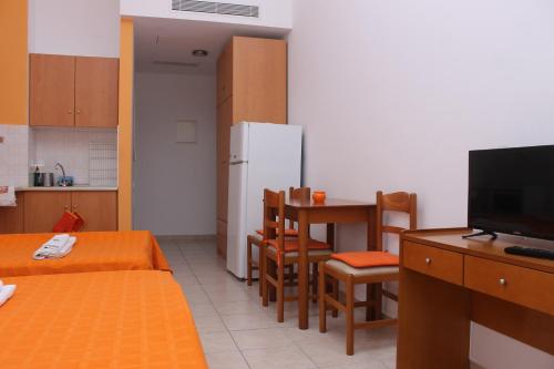 a small room with a kitchen and a table and a refrigerator at Angelos Studios in Ilia