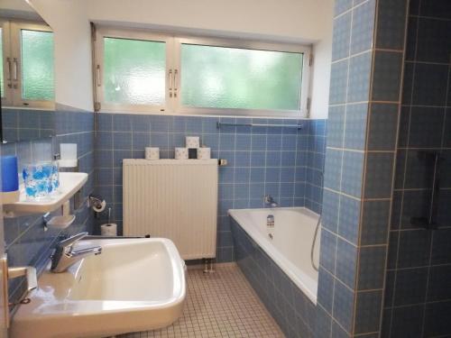 uma casa de banho em azulejos azuis com uma banheira e um lavatório em Villa Caroline em Pirmasens