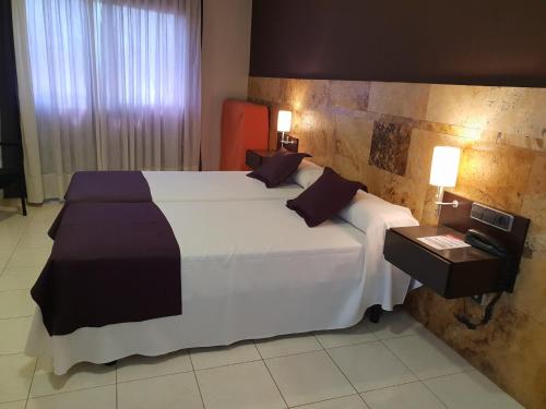 a bedroom with a large bed with white sheets and pillows at Hotel Spa Pinar del Mar in Platja  d'Aro