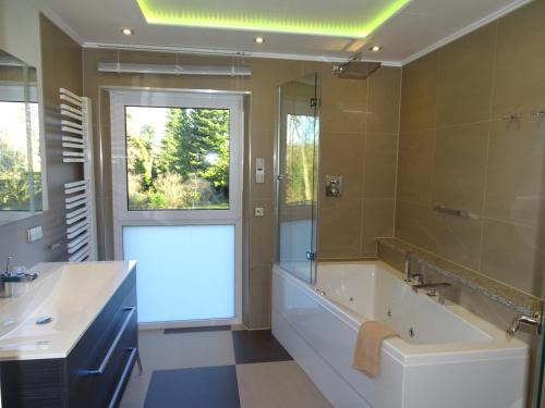 ein Badezimmer mit einer großen Badewanne und einem großen Spiegel in der Unterkunft * * * * * Villa Zabler in Bad Schonborn