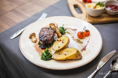 a plate of food with meat and potatoes on a table at Hotel Grand City Wrocław in Wrocław