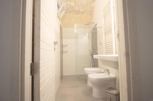 a white bathroom with a toilet and a sink at Il Giardino Della Regina in Gallipoli