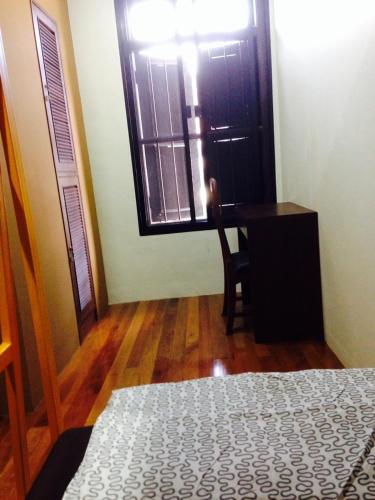 a bedroom with a bed and a desk and a window at Phuket Sunny Hostel in Phuket Town