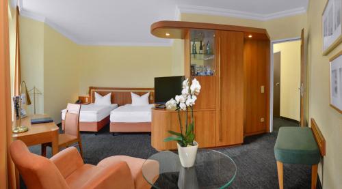 ヴィッテンにあるリングホテル パークホテル ヴィッテンのベッドとテーブルが備わるホテルルームです。