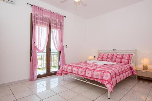 a bedroom with a pink bed and a window at Maria's House in Potamiá