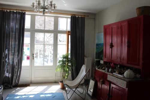 a kitchen with a white chair in front of a door at Les Mouettes in Saint-Suliac