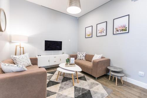 a living room with two couches and a tv at Suburban Bliss Durbanville in Kraaifontein