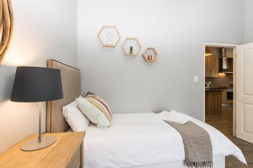a bedroom with a bed and a table with a lamp at Suburban Bliss Durbanville in Kraaifontein