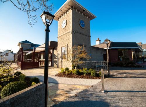 a clock tower in front of a building with a street light at Treacys West County Conference and Leisure Centre in Ennis