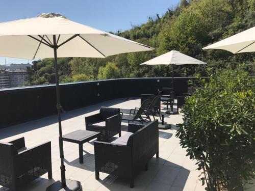 a row of tables and chairs with umbrellas on a roof at Talo Urban Rooms in Donostia-San Sebastián