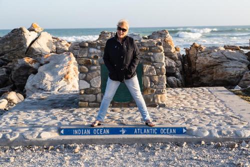 a man standing on top of anatlantic ocean sign at The Goose Nest in Struisbaai
