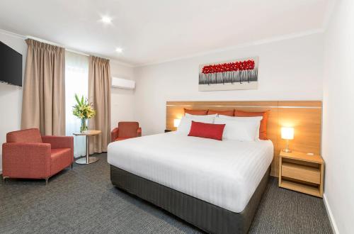 a hotel room with a bed and a red chair at Adelaide Royal Coach in Adelaide
