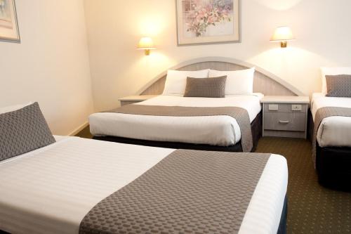 a hotel room with two beds and two tables at Adelaide Royal Coach in Adelaide