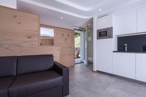 a living room with a couch and a television at Bellavista - Lake in Molveno