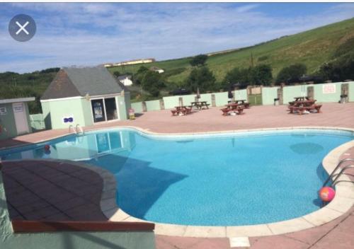 a large blue swimming pool with tables and benches at Take me to the beach at J&S caravan holidays Newquay Bay resort in Saint Columb Minor