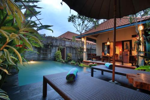 a house with a swimming pool with a table and an umbrella at The Forest Villa Ubud in Ubud