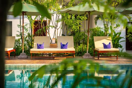 two chairs with purple pillows sitting next to a pool at Sabara Angkor Resort & Spa in Siem Reap