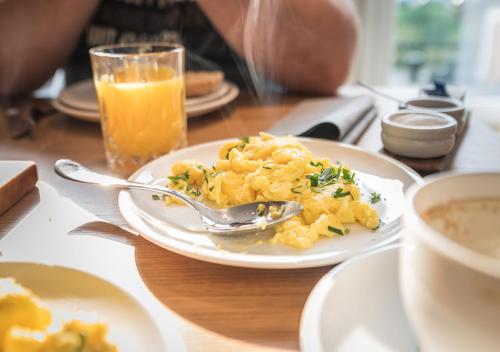 エルツァッハにあるHotel Restaurant Kochschule Rössleの食べ物の皿とオレンジジュースのグラスが置かれたテーブル