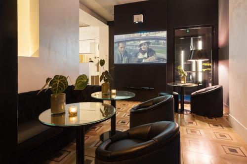 a living room with two tables and a tv at Senato Hotel Milano in Milan