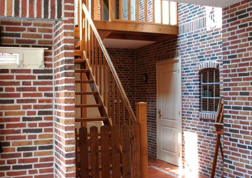 a brick hallway with a wooden staircase in a brick building at B&B Zandhuizen in Zandhuizen