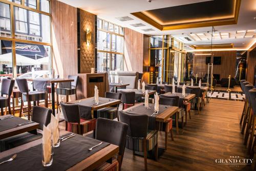 a restaurant with wooden tables and chairs and windows at Hotel Grand City Wrocław in Wrocław