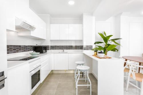 a white kitchen with white cabinets and a table at iloftmalaga Deluxe Alameda Principal in Málaga