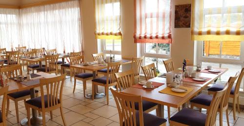a restaurant with wooden tables and chairs and windows at Frühstückspension Winter in Gössendorf