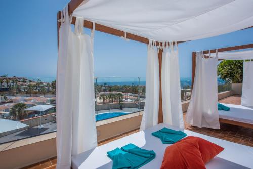 a bedroom with a bed and a balcony with a pool at Haciendas Village Tenerife in Adeje