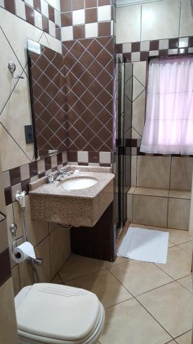 a bathroom with a sink and a toilet at Hotel Peroza Corbelia in Corbélia