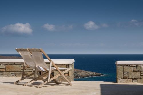 a wooden chair sitting on a balcony overlooking the ocean at Astrini in Kithnos
