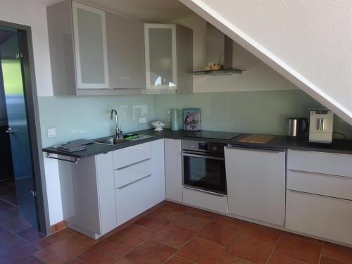 a kitchen with white cabinets and a sink at Ferienwohnung Haus am Barg in Heikendorf