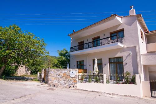 a white house with a balcony on a street at On The Rocks in Theologos