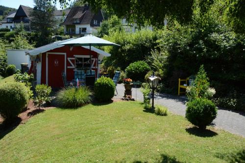 a small red shed with an umbrella in a yard at Ferienwohnung Burgblick Bilstein in Bilstein