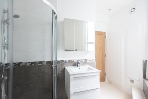 een badkamer met een witte wastafel en een douche bij The Mayfair Parade - Trendy 1BDR in Londen