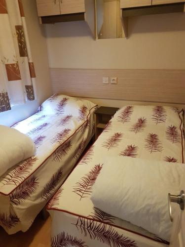 レ・マトゥにあるMobil Home 3 CH - 2 SDB - Tout Confortのベッド2台が隣同士に設置された部屋です。