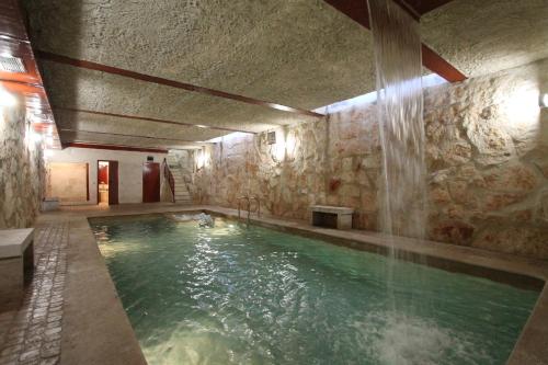 a swimming pool in a stone building with a water feature at Apartamentos Villablino Arturo Soria in Madrid
