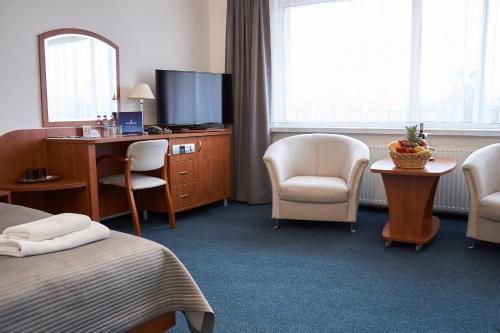 a hotel room with a bed and chairs and a tv at Hotel Unitral SPA w Mielnie in Mielno